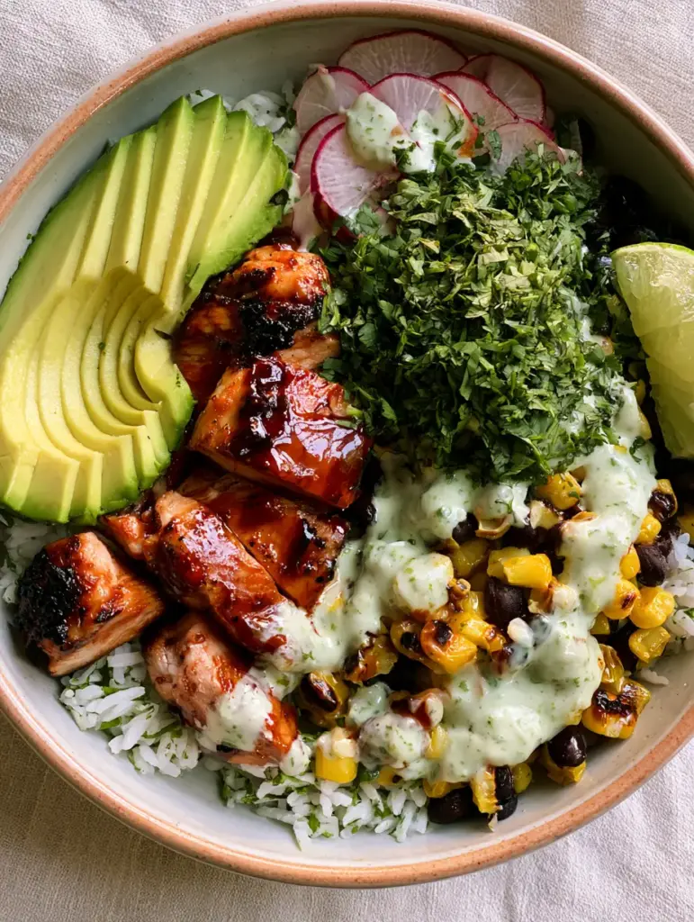 Honey Lime Chicken Avocado Bowl with Cilantro Lime Rice 1 A vibrant ceramic bowl filled with the Honey lime chicken avocado bowl ingredients including black beans and red radishes.
