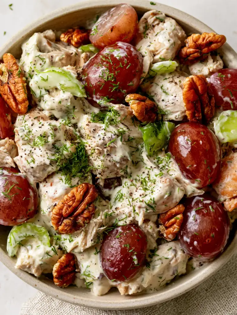 Chicken Salad With Grapes: The Ultimate Creamy Roasted Version 1 A bowl of chicken salad with grapes featuring toasted pecan halves and coarse black pepper specks on a linen napkin.