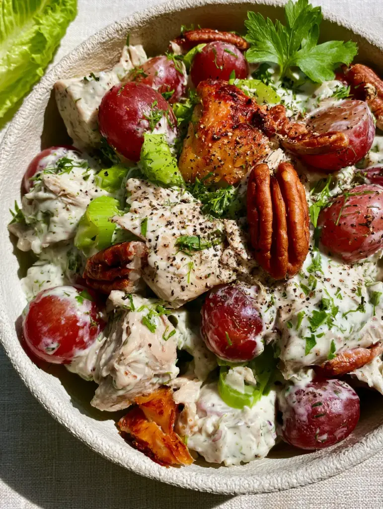 Detailed shot showing the texture of toasted pecan halves and sliced red grapes in a creamy chicken salad. (Chicken Salad Recipes)