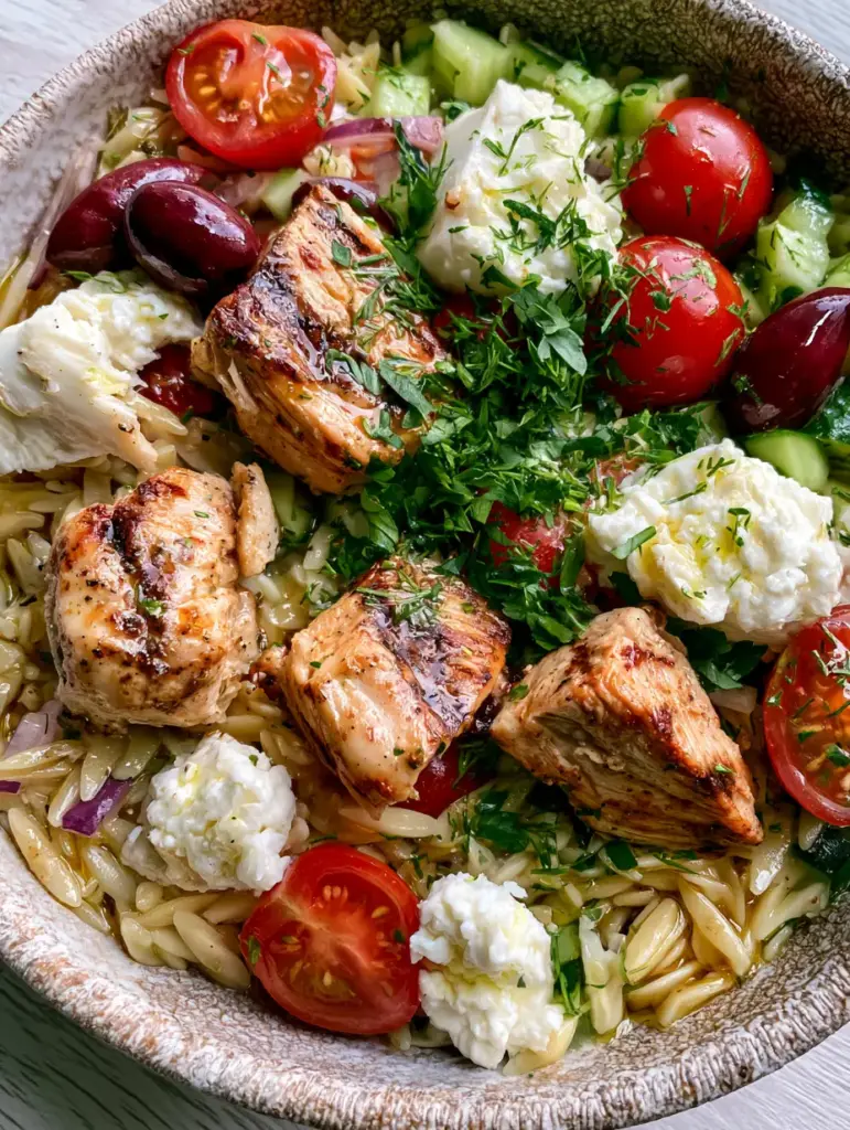 Greek chicken orzo salad with Lemon Herb Vinaigrette 1 Greek chicken orzo salad served in a ceramic bowl with visible grill marks on the chicken.