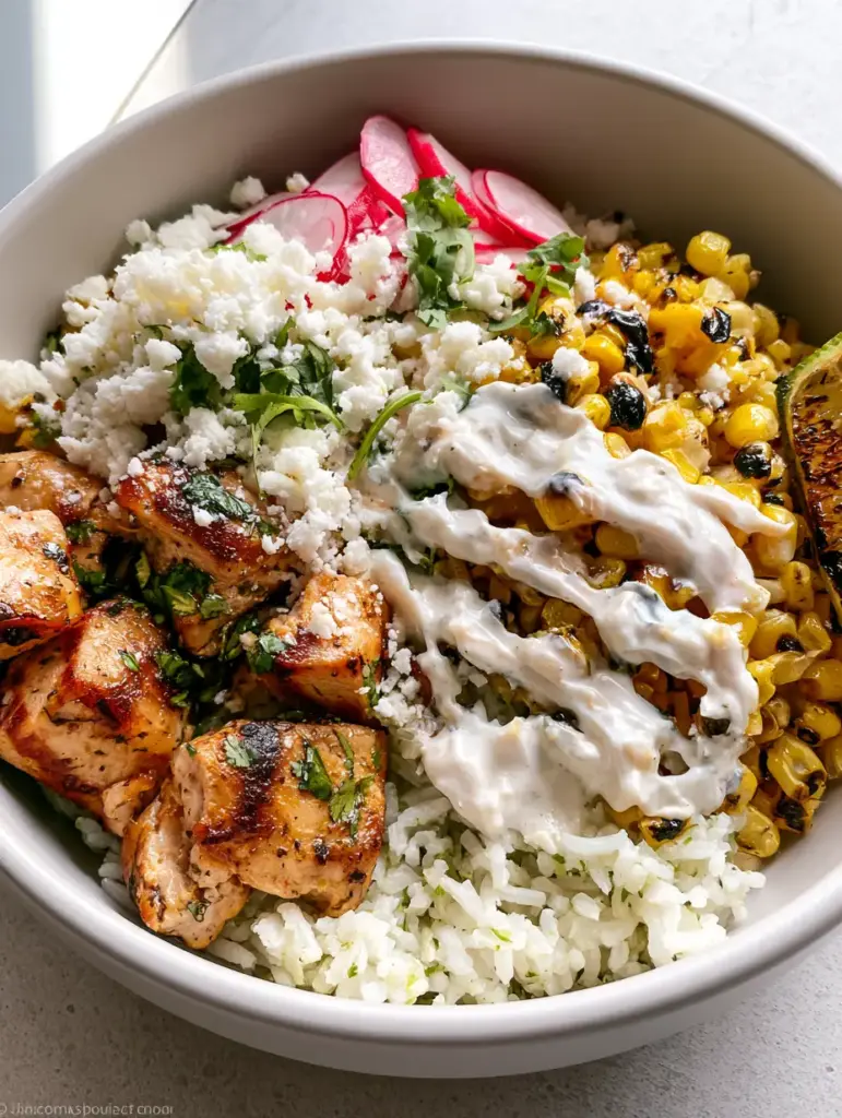 Street Corn Chicken Bowl with Charred Corn and Zesty Lime Crema 1 Modern matte white bowl filled with street corn chicken bowl ingredients and a heavy zig-zag of lime crema.